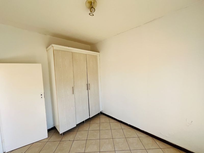 A vacant bedroom featuring tiled flooring and a built-in wardrobe, offering a blank canvas for personalization.