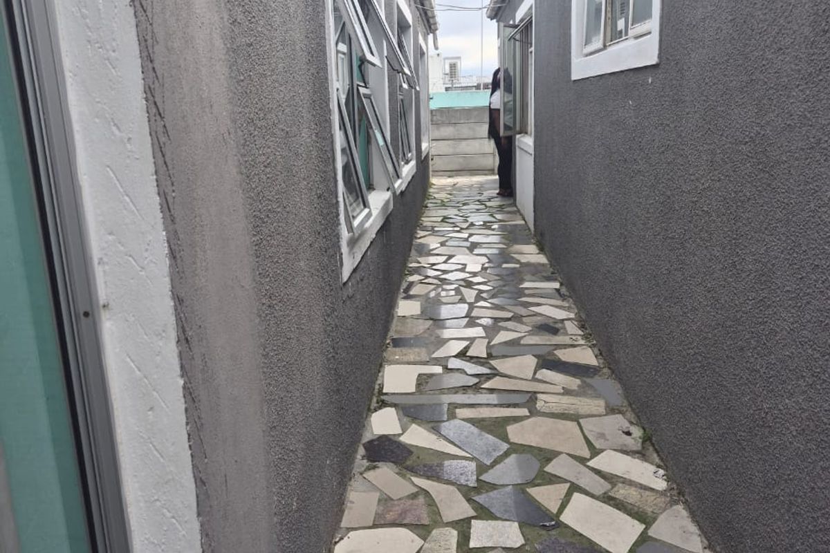 A narrow side passage between two building sections featuring stone crazy paving and multiple casement windows.