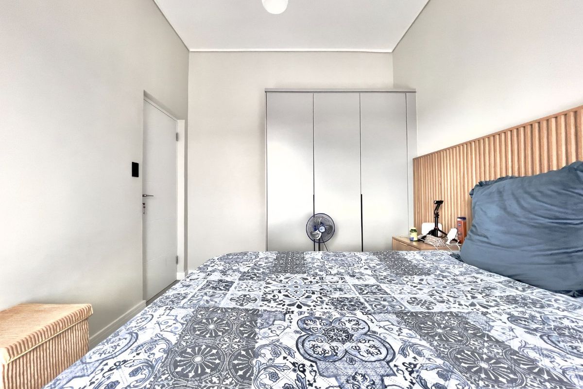 A well-maintained bedroom featuring a modern slatted timber headboard and integrated built-in wardrobe storage.