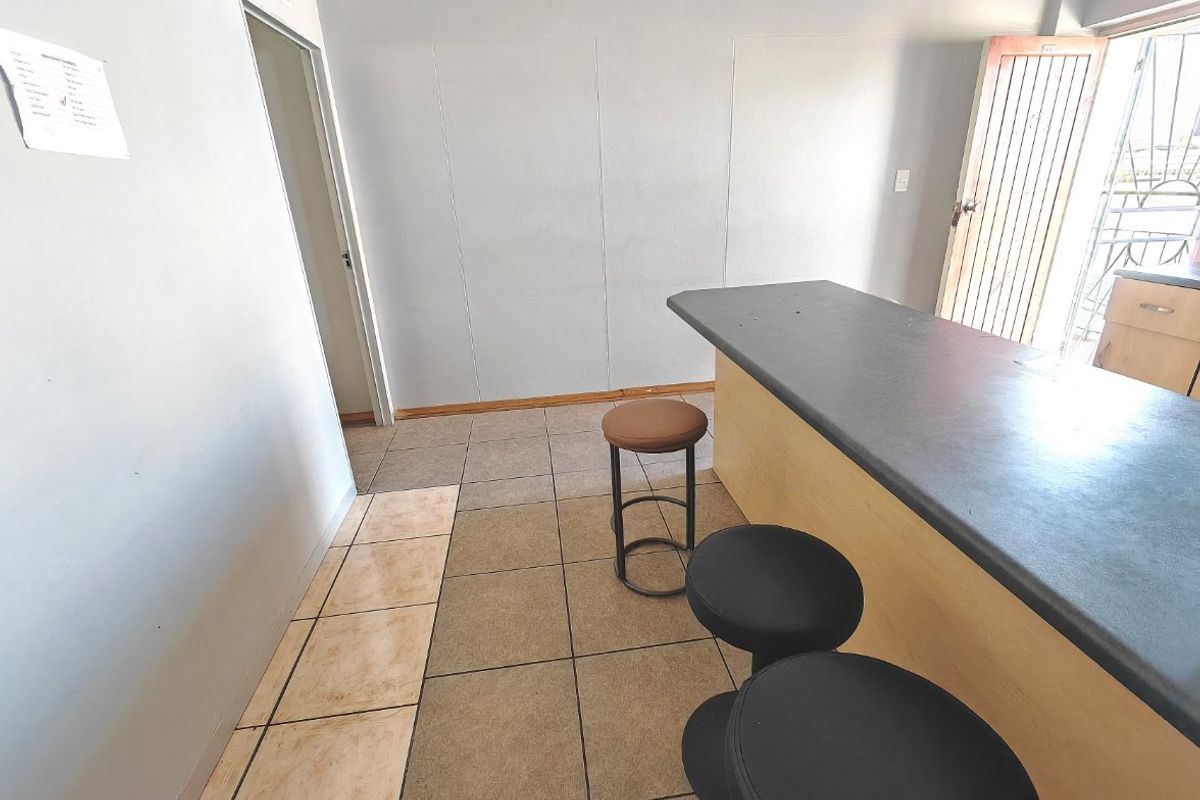 Open plan living area featuring a breakfast bar, tiled flooring, and access to an exterior entrance with a security gate.