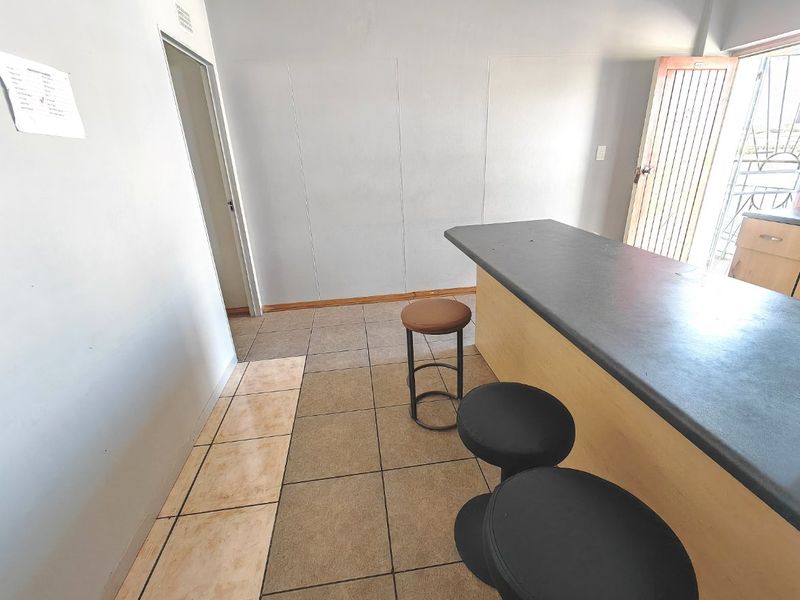 Open plan living area featuring a breakfast bar, tiled flooring, and access to an exterior entrance with a security gate.
