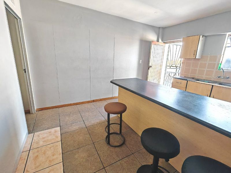 Open plan kitchen area featuring a breakfast bar, tiled backsplash, and functional cabinetry, providing a practical layout for daily living.
