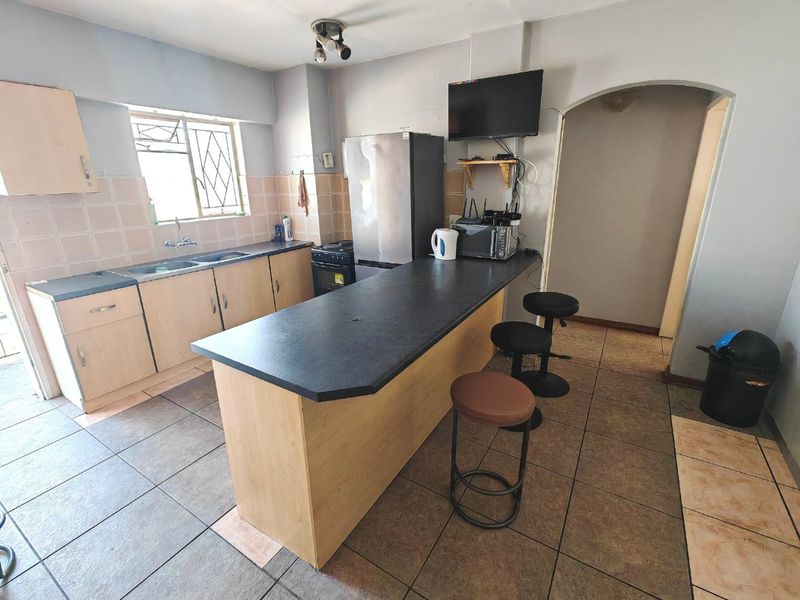 Functional kitchen featuring laminate cabinetry, a breakfast bar, double basin sink, and tiled flooring with a neutral backsplash.