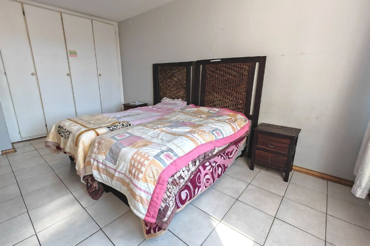 A bedroom featuring tiled flooring and built-in cupboards, providing functional storage space.
