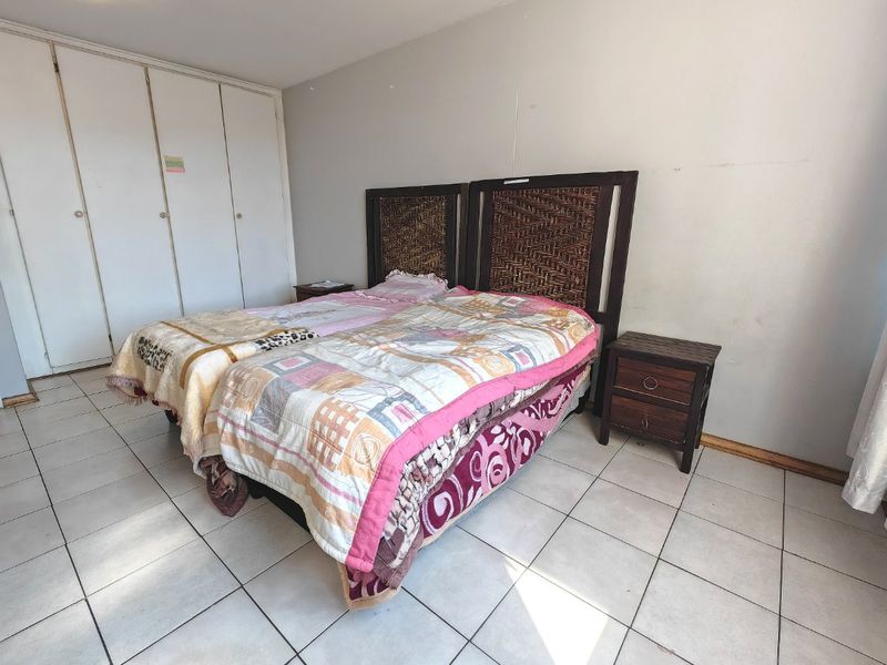 A bedroom featuring tiled flooring and built-in cupboards, providing functional storage space.