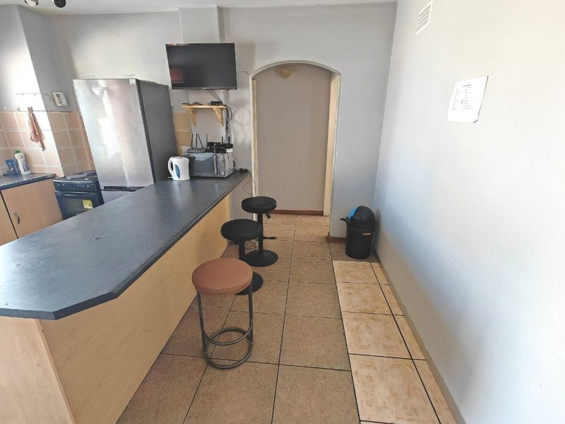 A compact kitchen area featuring a breakfast bar, tiled flooring, and built-in cabinetry with an integrated oven and hob.