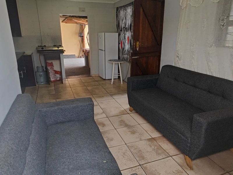Open plan living area featuring tiled flooring and a compact kitchen space with built-in cabinetry and a gas stove.
