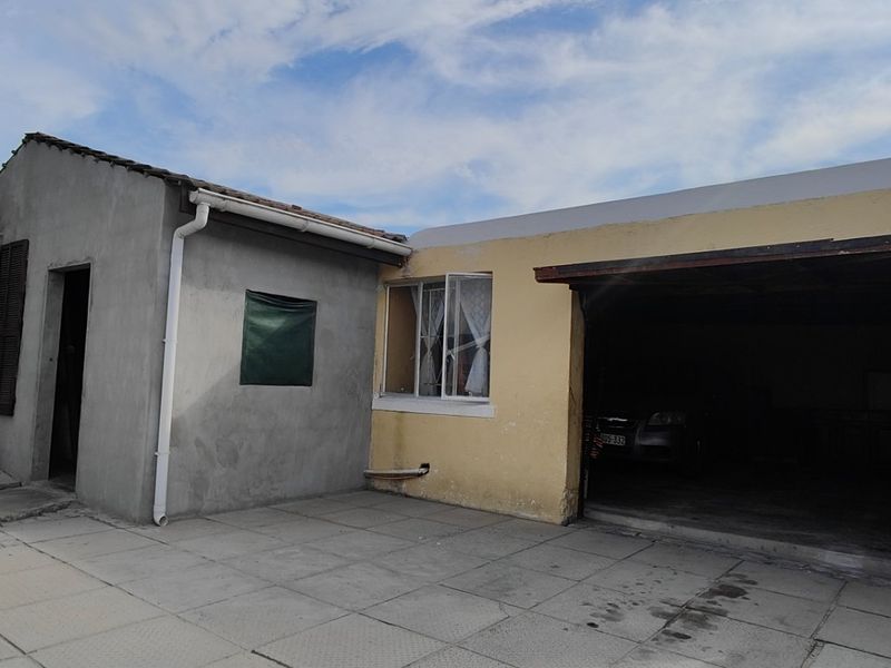 Front exterior view of the property featuring a garage, paved driveway, and unfinished plasterwork on the main building facade.