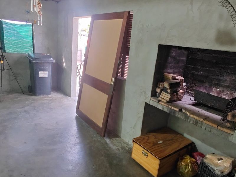 An unfinished covered patio area featuring a built-in brick braai and raw concrete walls, offering potential for a customized outdoor entertainment space.