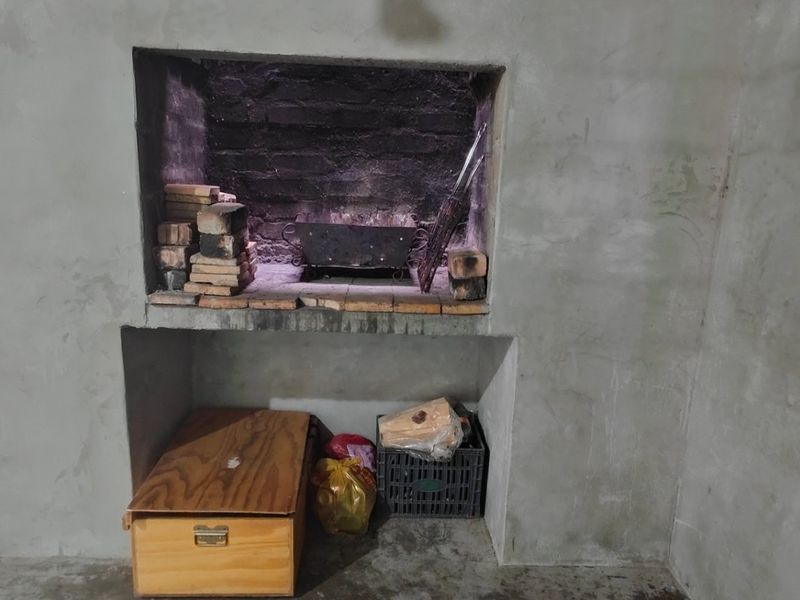 An indoor braai area featuring a built-in fireplace with raw concrete walls, offering a rustic space ready for finishing or renovation.