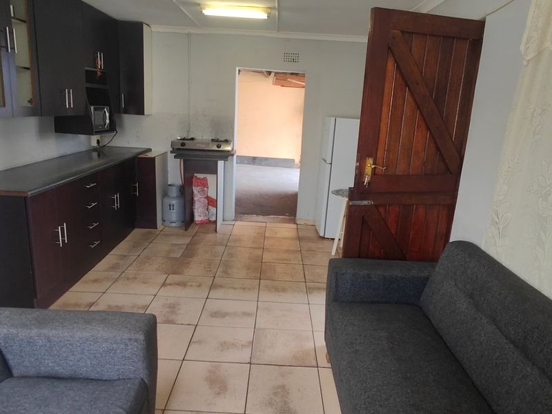 Open plan living and kitchen area featuring dark cabinetry, tiled flooring, and direct access to an adjacent utility space.