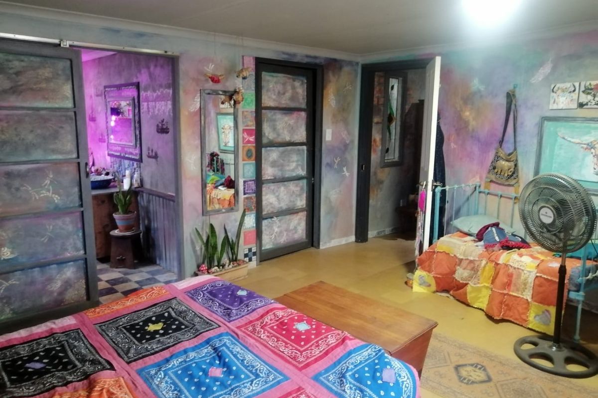 A bedroom featuring unique decorative wall finishes, laminate flooring, and access to an adjoining room through sliding and standard doors.