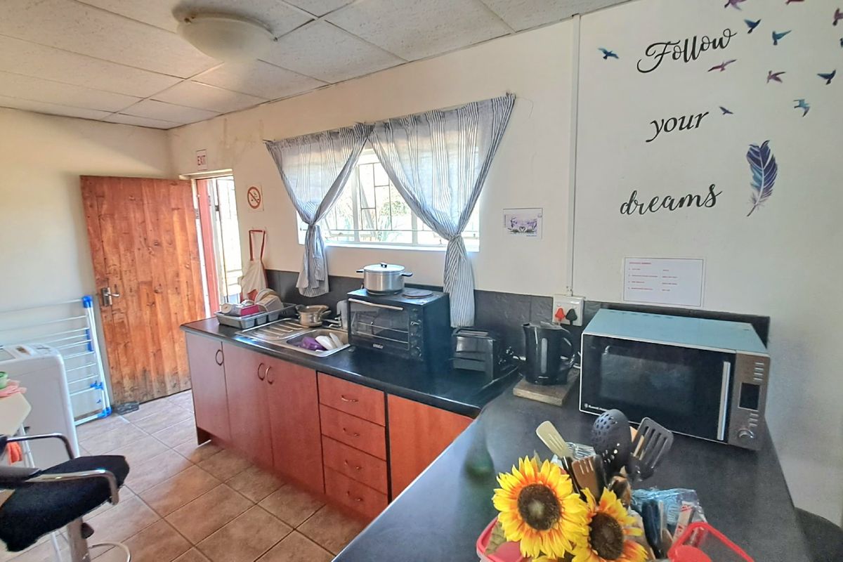 A functional kitchen area featuring laminate cabinetry, dark countertops, and tiled flooring, offering a practical layout for daily meal preparation.