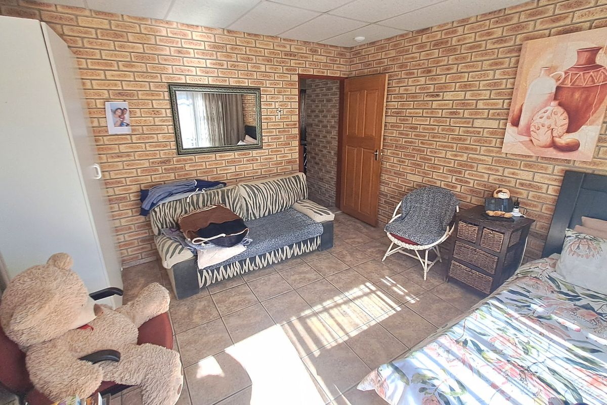 A bedroom featuring exposed brick walls, tiled flooring, and a drop ceiling, offering a rustic aesthetic with potential for modernization.