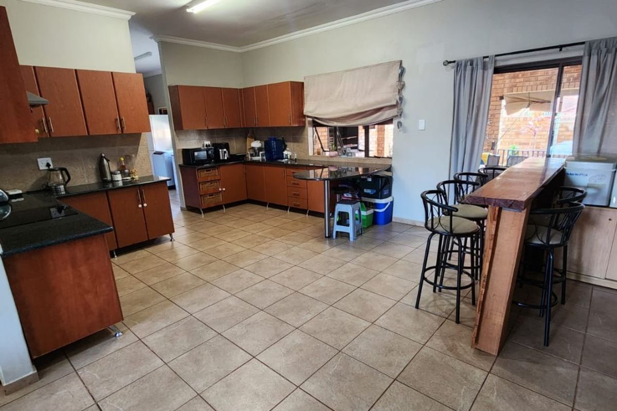 Spacious kitchen featuring wooden cabinetry, granite countertops, and a breakfast bar, with direct access to the outdoor patio area.