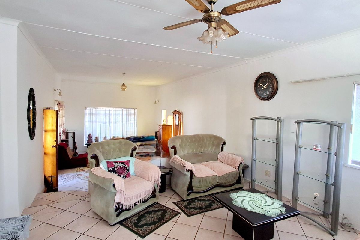 Spacious living room featuring tiled flooring, a ceiling fan, and coved ceilings, offering a versatile layout for comfortable family living.