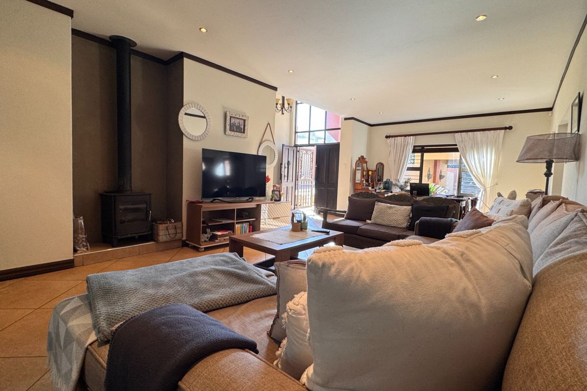 Spacious living room featuring tiled flooring, a freestanding fireplace, and large sliding glass doors providing natural light and access to the exterior.