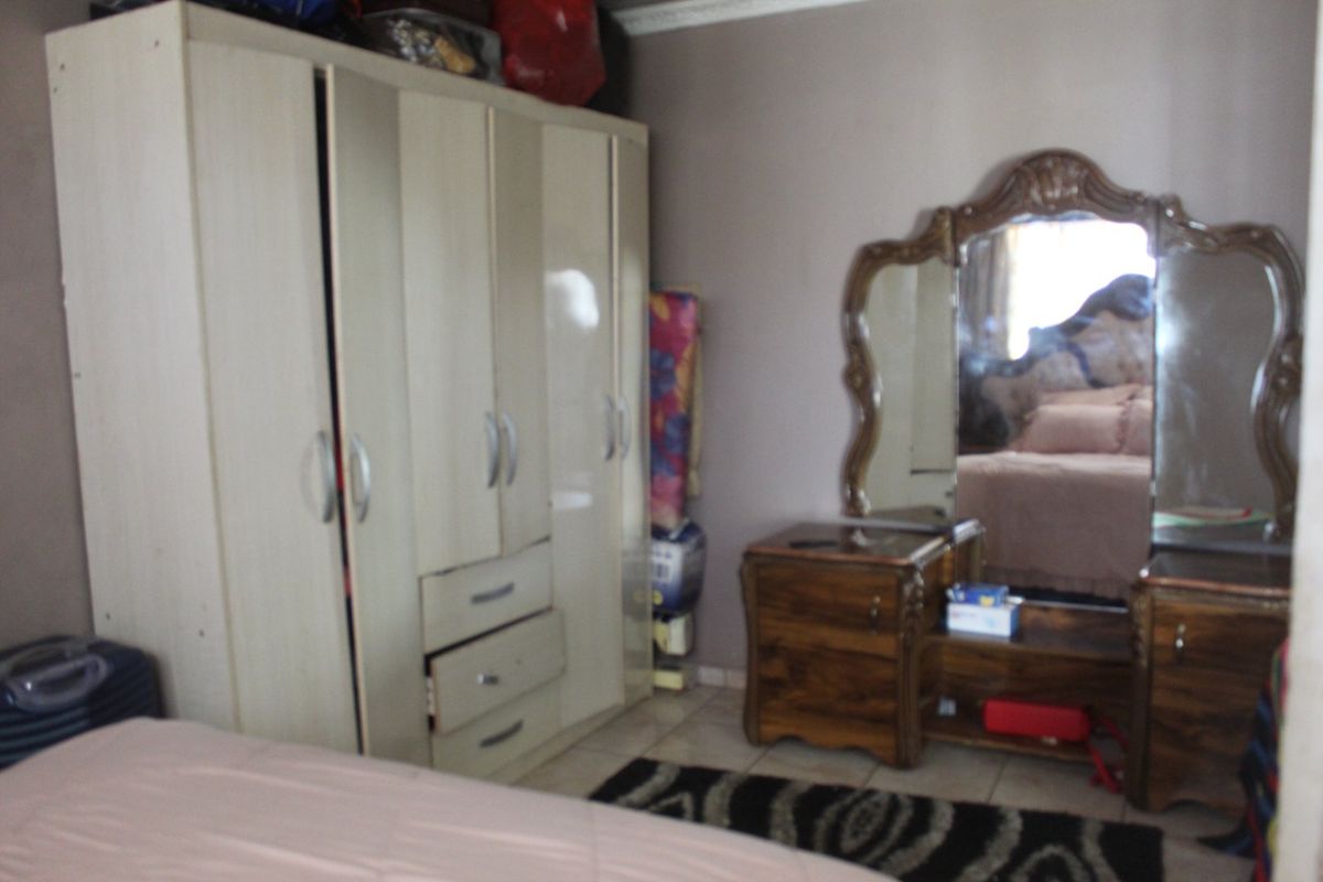 A bedroom featuring a large built-in wardrobe with integrated drawers and tiled flooring.