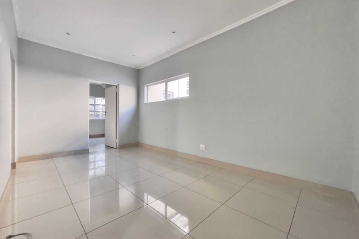 A clean, vacant bedroom featuring neutral wall tones, polished floor tiles, and recessed lighting, offering a versatile space ready for personalization.