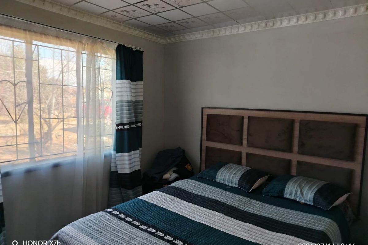 A bedroom featuring decorative ceiling tiles, crown molding, and security bars on the window.