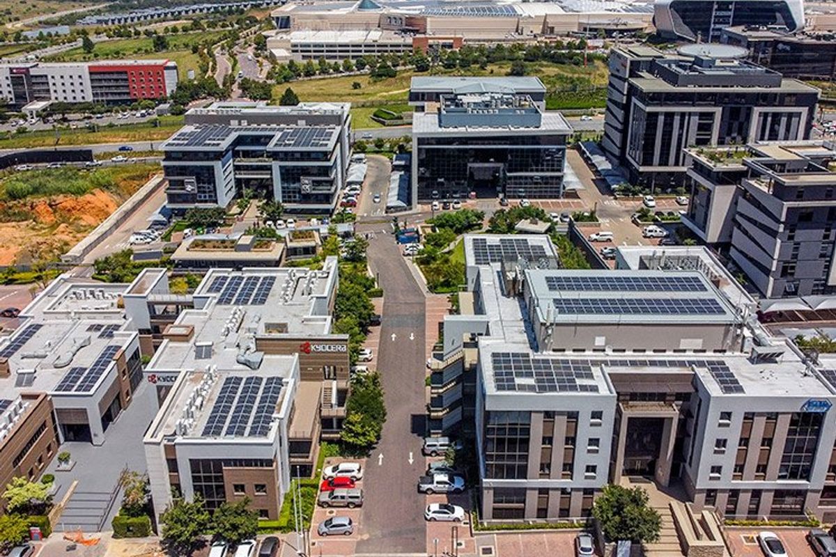 Aerial view of a modern commercial office park featuring multiple buildings with rooftop solar installations and integrated parking facilities.