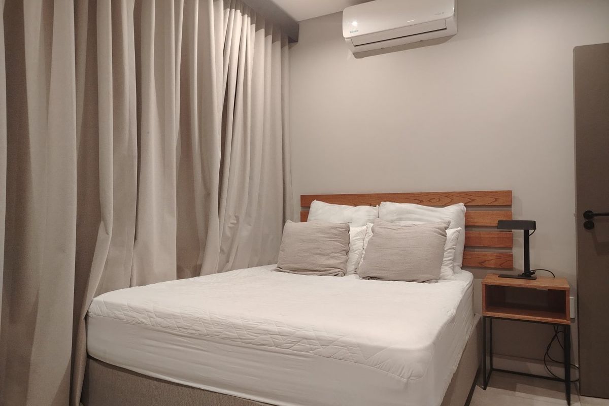 A well-maintained bedroom featuring a wall-mounted air conditioning unit, timber headboard, and neutral tiled flooring.