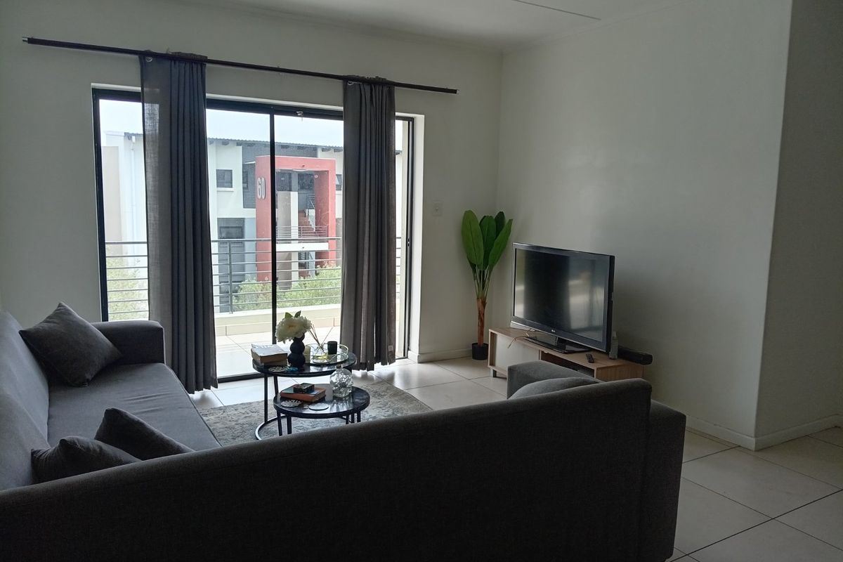 A living room featuring tiled flooring and a large sliding glass door providing access to an outdoor balcony area.