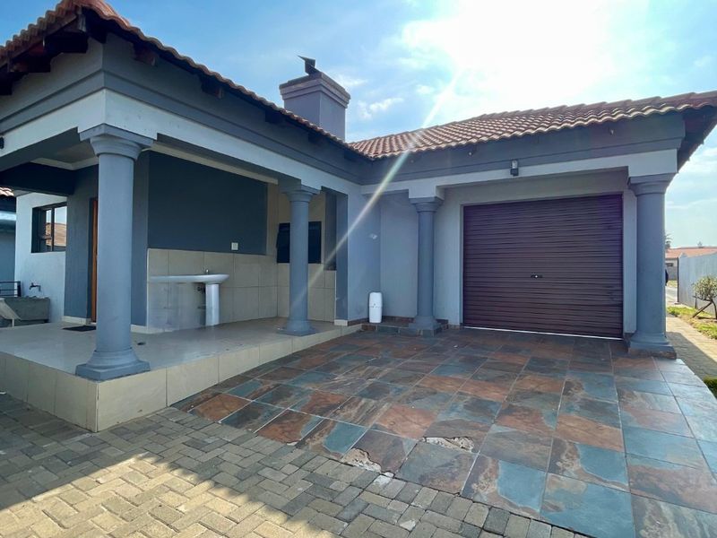 Front exterior view of the house featuring a covered patio with concrete columns, a tiled driveway, and an integrated garage.