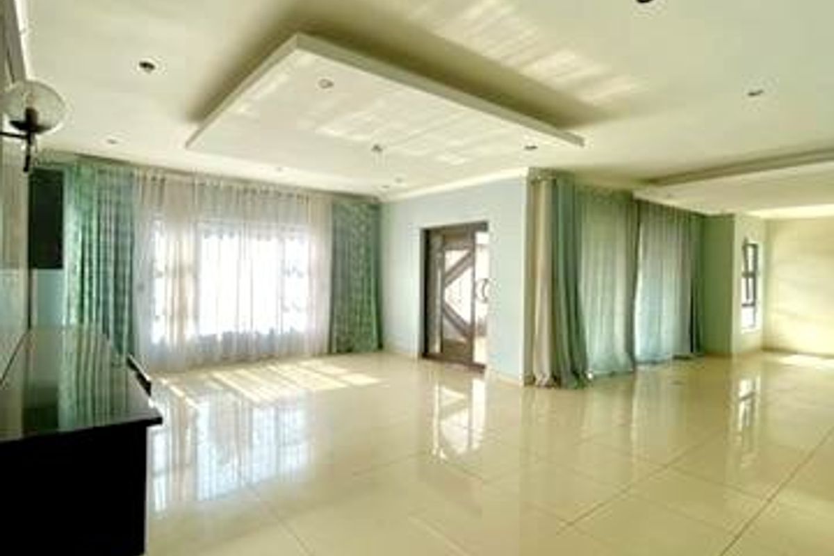 A spacious, light-filled living area featuring polished tile flooring, a modern recessed ceiling with downlights, and large sliding glass doors.