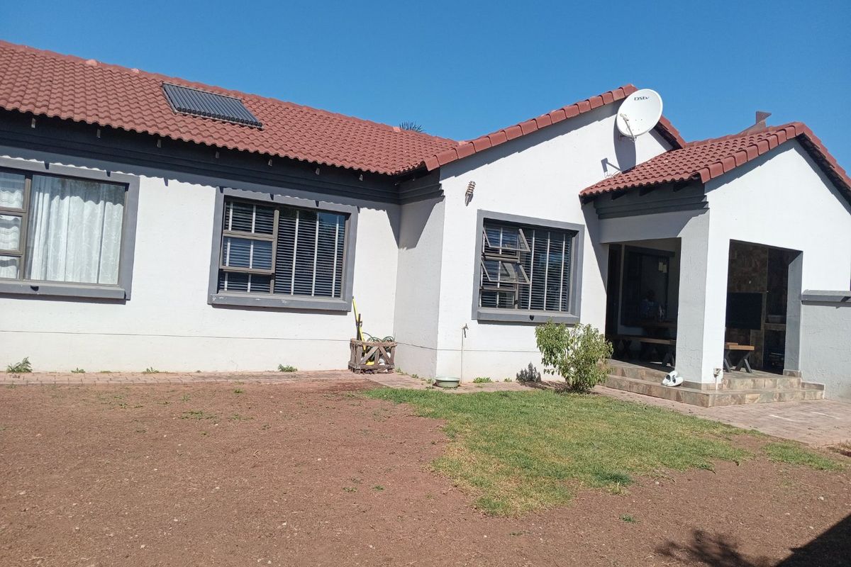 Rear view of the house featuring a tiled roof with solar panel, aluminium windows, and a covered patio area with stone cladding.