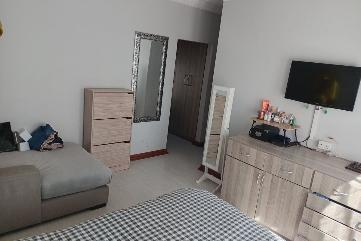 A bedroom featuring laminate flooring, coving, and a built-in cupboard, providing a functional living space with neutral wall finishes.