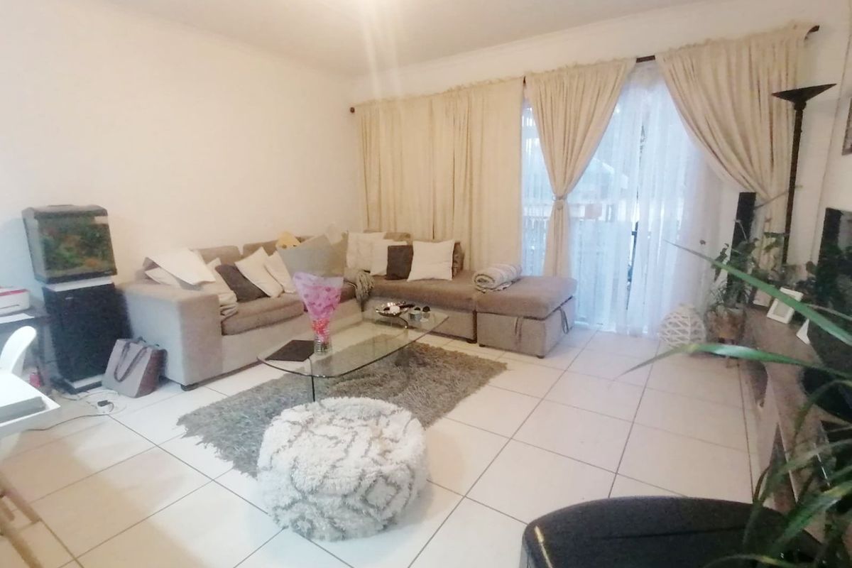 A living room featuring tiled flooring and a sliding glass door providing access to the exterior.