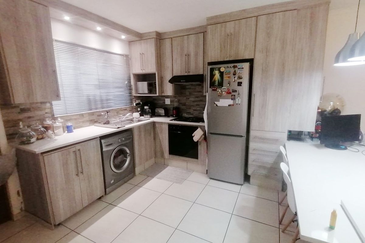 A functional kitchen featuring wood-look cabinetry, stone countertops, integrated appliances, and tiled flooring, offering a practical layout for daily use.