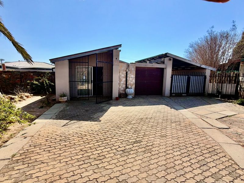 Front exterior view of the property featuring a paved driveway, single garage, and secure entrance with stone cladding accents.