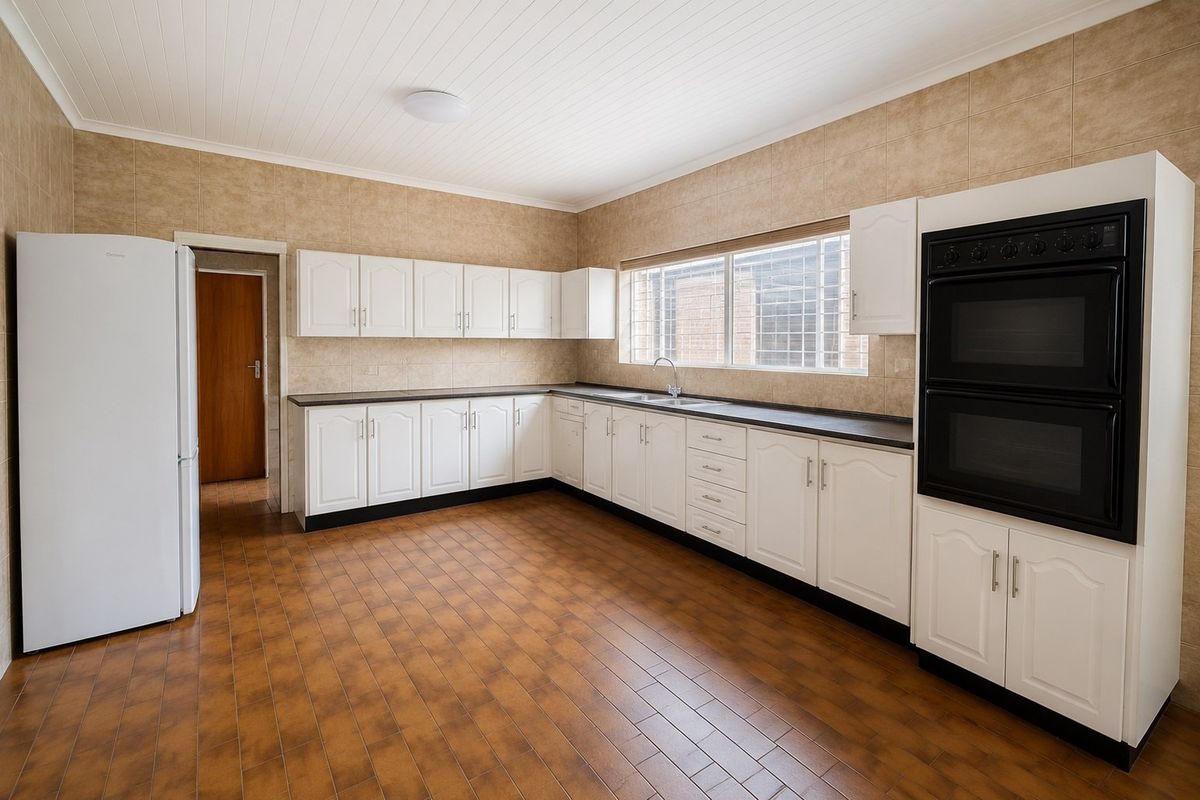 Spacious kitchen featuring white cabinetry, dark countertops, a built-in double oven, and tiled flooring. The room is clean and ready for modern updates.