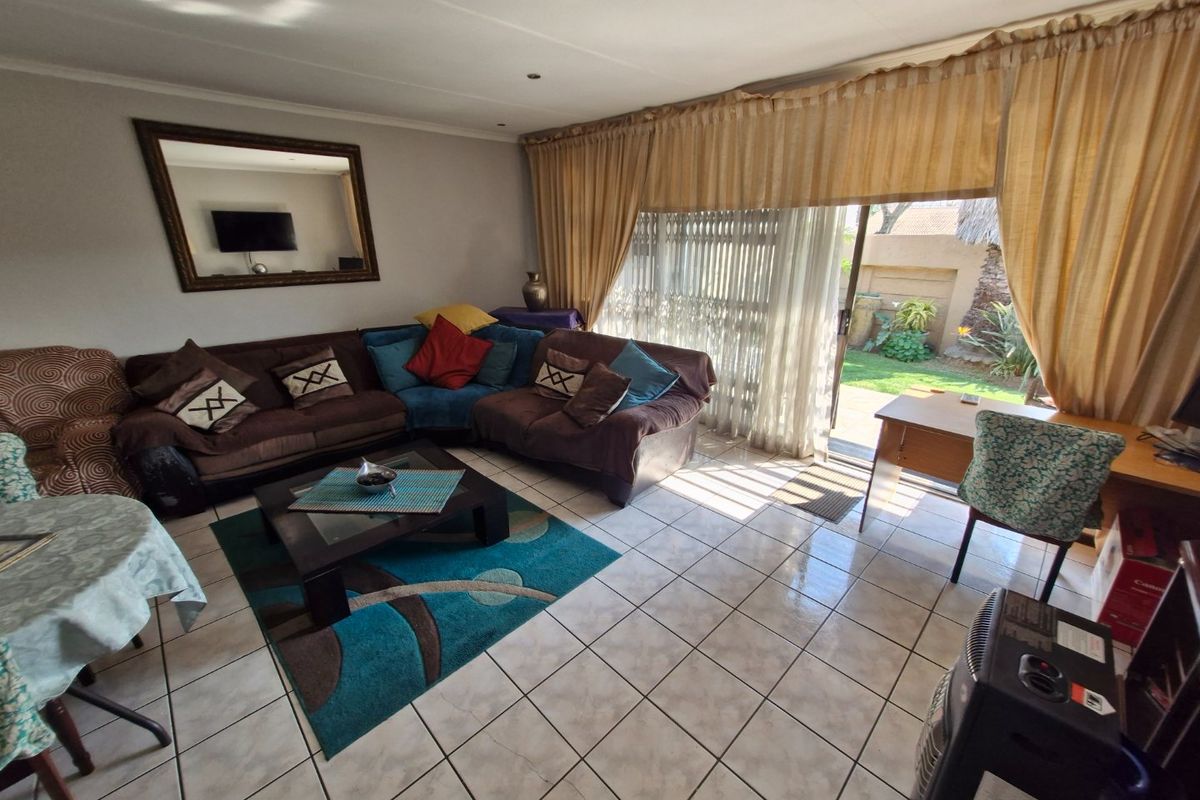A spacious living room featuring tiled flooring and a large sliding glass door providing direct access to the rear garden area.