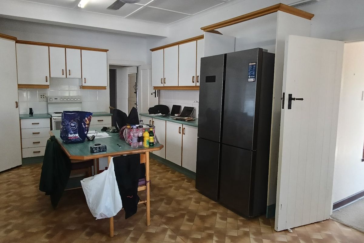 A functional kitchen featuring ample built-in cabinetry, laminate countertops, and a freestanding stove, offering a practical layout with potential for modern updates.