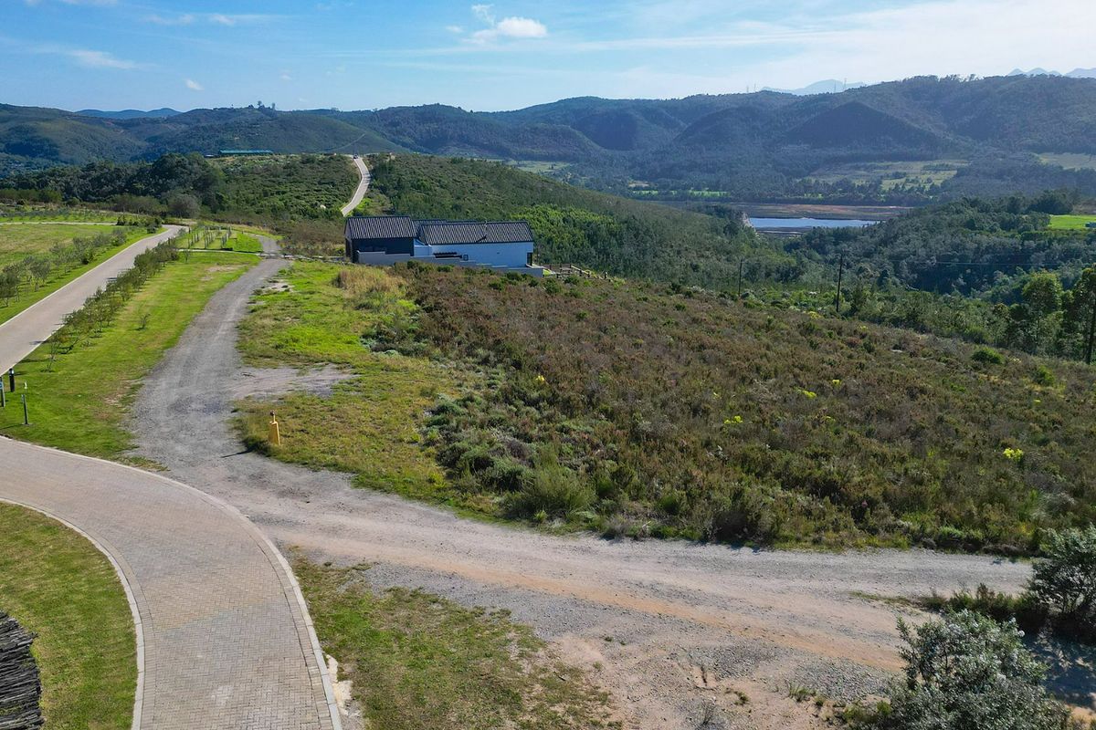 Aerial view of a residential vacant land plot featuring paved and gravel access roads with scenic mountain and landscape views.