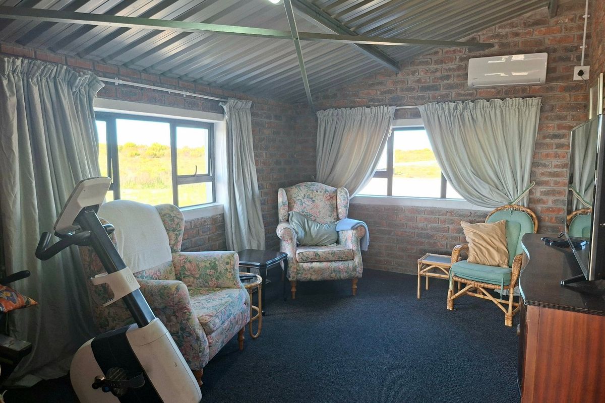 A rustic living area featuring exposed brick walls, a high corrugated metal ceiling, and split-system air conditioning with views of the surrounding landscape.