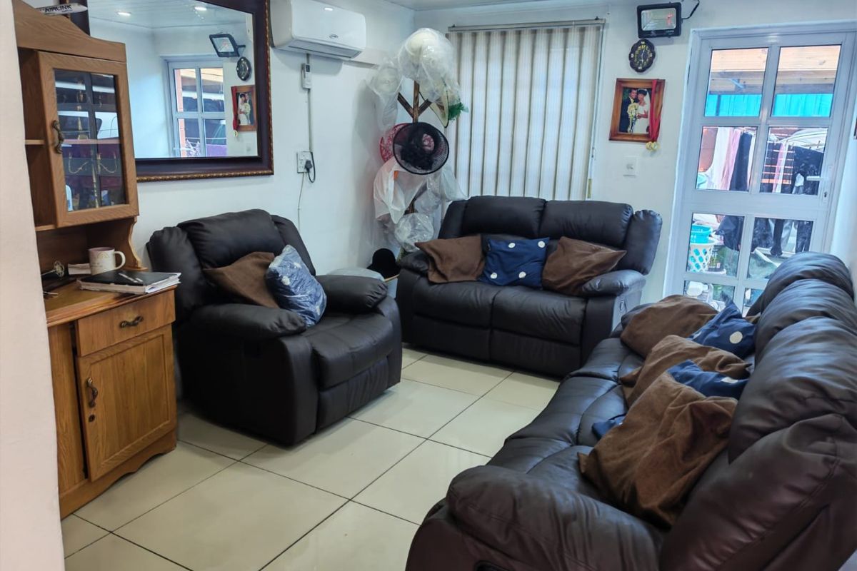 A comfortable living room featuring tiled flooring, recessed ceiling lighting, and an integrated air conditioning unit, with direct access to an outdoor area.
