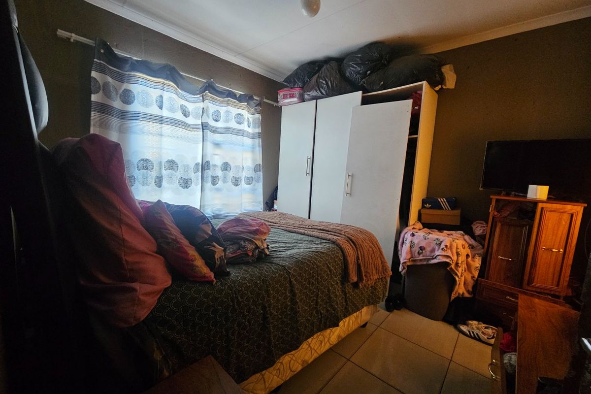 A bedroom featuring tiled flooring and a built-in wardrobe, offering a functional space that could benefit from cosmetic updates.