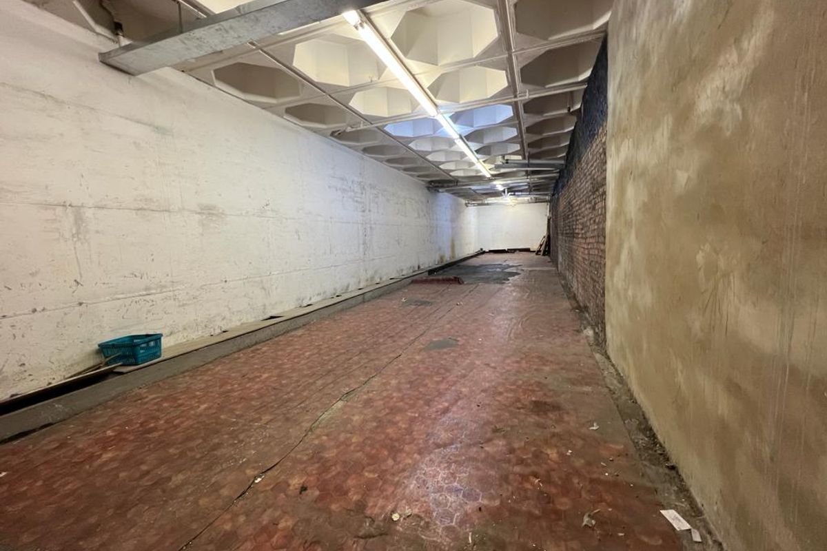 An expansive, empty industrial utility space featuring a distinctive waffle slab ceiling, exposed brickwork, and concrete walls, suitable for storage or workshop conversion.