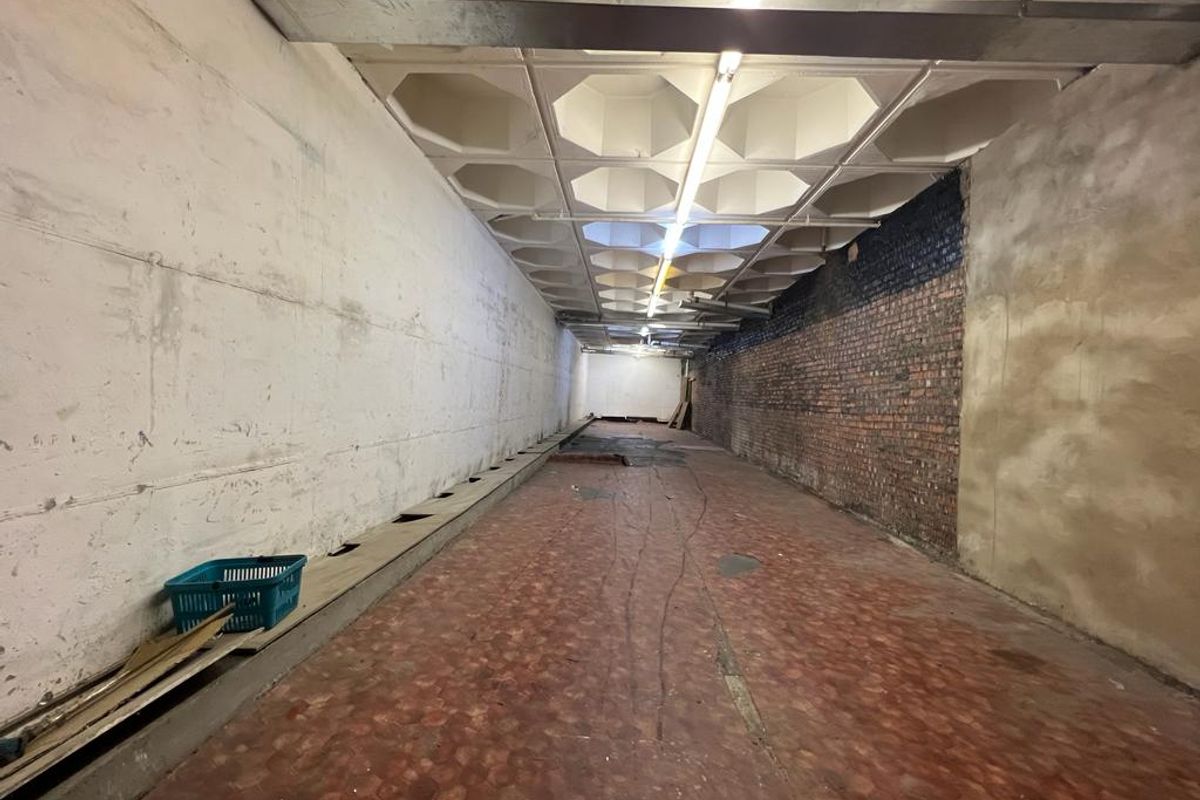 A large, vacant industrial utility space featuring a distinctive waffle slab ceiling, exposed brickwork, and concrete flooring, suitable for various commercial or storage uses.