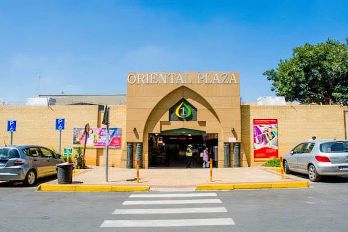 Front elevation of the Oriental Plaza industrial and retail complex, featuring a prominent arched entrance and paved access area.