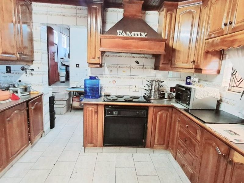 A traditional kitchen featuring wooden cabinetry, built-in oven, electric hob, and tiled splashbacks, offering a functional layout with potential for modern updates.