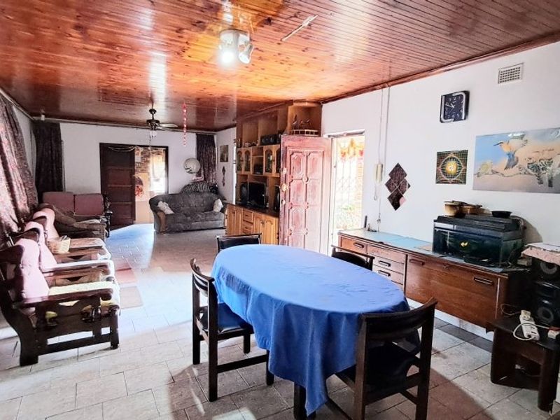 Open plan living and dining area featuring a timber tongue and groove ceiling, tiled flooring, and built-in cabinetry.