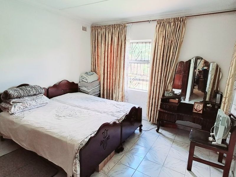 A functional bedroom featuring tiled flooring and a window with security bars, offering a neutral space ready for modernization.