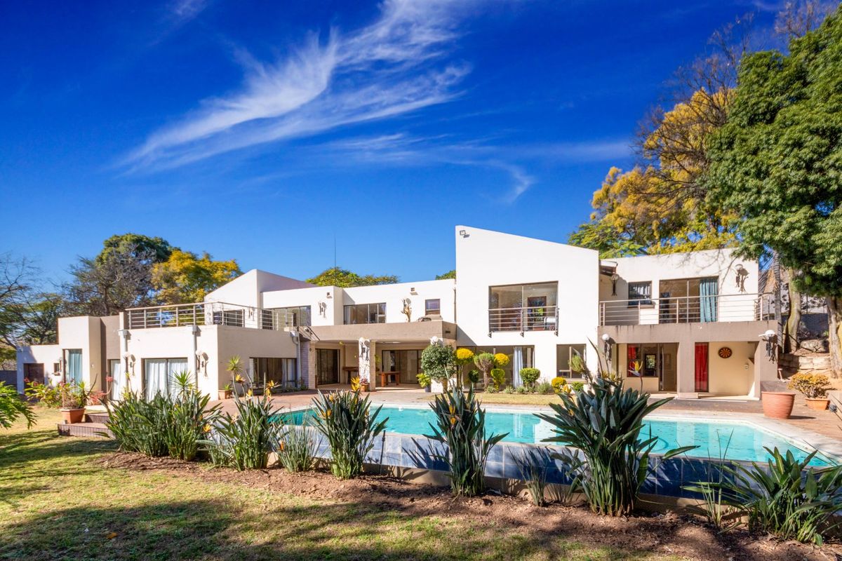 Spacious rear exterior view featuring a swimming pool, multi-level balconies with metal railings, and established garden landscaping.