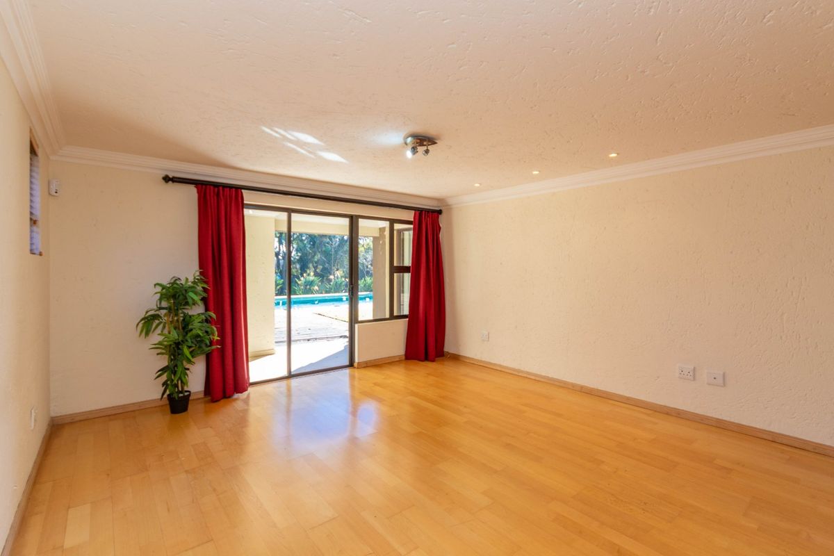 Spacious living room featuring laminate flooring, textured walls, and large sliding glass doors providing direct access to the outdoor pool area.