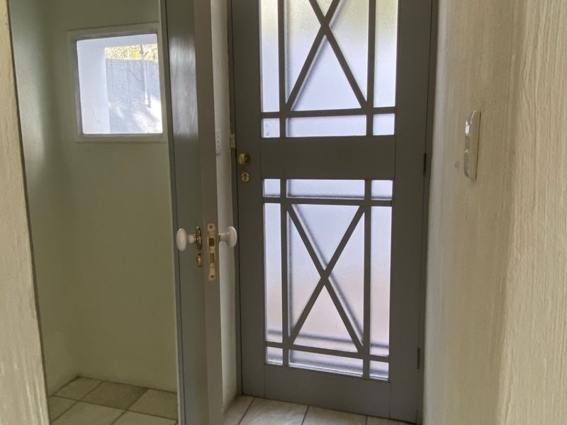 An entry area featuring tiled flooring and a decorative frosted glass panel door, showing signs of wear and requiring cosmetic updates.